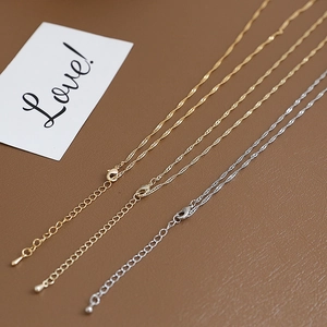 Detail of adjustable gold and silver flat O-chains with lobster clasps on leather