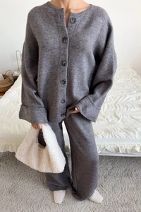Detail of dark grey knitted cardigan and wide-leg pants set in a cozy home setting