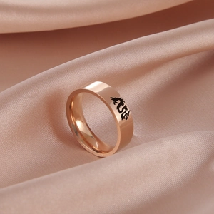 Vista macro di un anello in oro rosa con incisione a drago su seta color champagne
