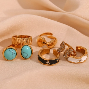 Detailed view of assorted 18K gold plated rings with turquoise and enamel on silk