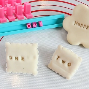 Macro view of alphabet cookie stamp set on silicone mat for DIY baking and decorating