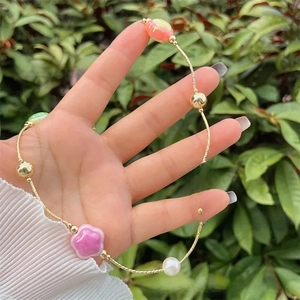 Close-up of gold chain with colorful pearlescent flower beads and a white pearl