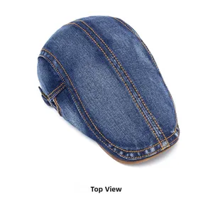 Top view of dark blue denim flat cap with orange stitching and side metal buckle