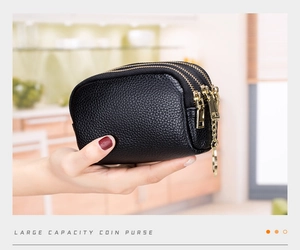 Detail of black pebbled leather coin purse with triple zippers and golden keychain