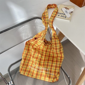 Detail of embroidered plaid canvas tote bag hanging on a chair with a minimalist aesthetic