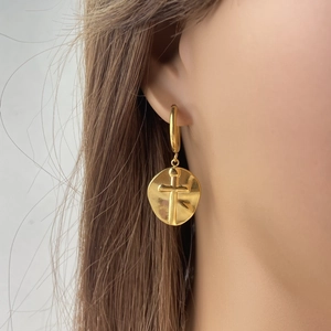 Primo piano di un orecchino a medaglione con croce e stella placcato in oro 14K da modella