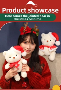Close-up of a white plush Christmas teddy bear with movable joints and festive red hat