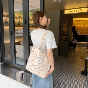 Floral canvas tote bag with purple prints shown in a stylish cafe street scene
