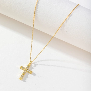 Macro detail of gold-plated cross pendant necklace featuring brilliant zircon stones