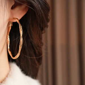 Close-up of vintage round gold earrings with handcrafted hammered texture on model
