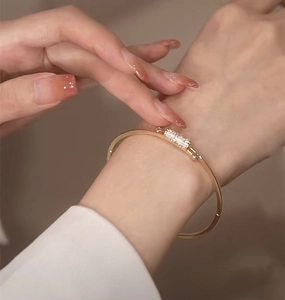 Detailed close-up of a gold-plated bracelet with a zircon-encrusted cylindrical pendant