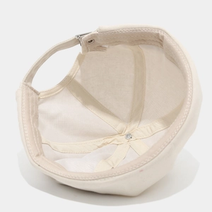 Detailed interior of beige cotton beanie showing reinforced seams and metal buckle strap
