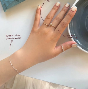 Close-up of a minimalist 925 sterling silver bubble chain bracelet and beaded rings set