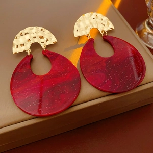 Macro detail of red resin drop earrings with gold hammered metal and marble texture