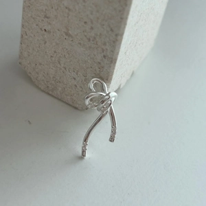 Detailed view of silver bow earrings with sparkling cubic zirconia on stone background