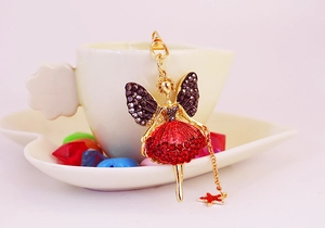 Detail eines Engels-Schlüsselanhängers mit roten Steinen an einer weißen Tasse