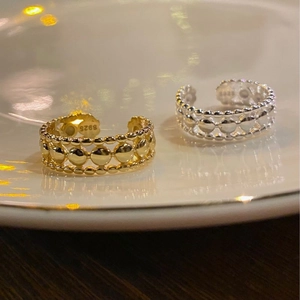 Detail of S925 sterling silver hollow bead rings in gold and silver finish on porcelain