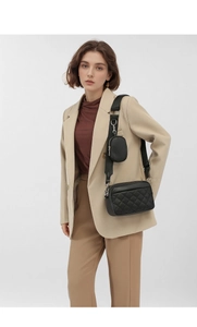 Detail of black quilted crossbody camera bag with wide strap and small round coin purse