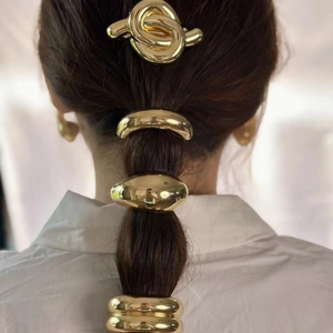 Close-up of golden alloy U-shaped ponytail holder and knot hair clip on hair