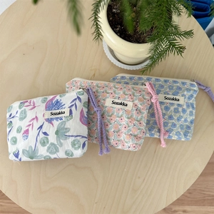 Dettagli di pochette in tela floreale con lacci a coulisse e trama in cotone rustico