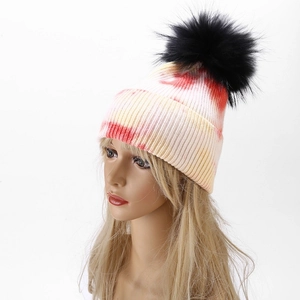 Macro view of tie-dye knit beanie with fluffy black pom pom and ribbed texture