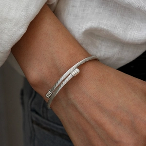 Close-up of twisted cable cuff bracelet with striped end caps on a model's wrist
