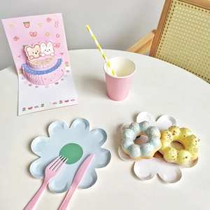 Flat lay of daisy flower paper plates with pink cutlery and a 3D birthday card