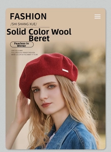 Detail of red wool beret with metal logo plaque paired with blue denim jacket