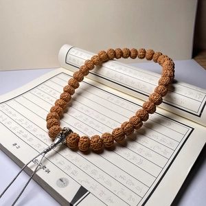 Close-up of Nepal Bodhi seed bracelet with vintage silver charm on traditional book
