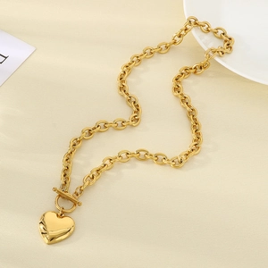 Detail of gold heart pendant with OT toggle clasp and chunky link chain on a fabric background