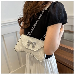 Detailed close-up of a white sequined handbag with a sparkling silver bow decorative detail