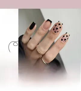 Detail of short square French nails with black tips and small heart patterns