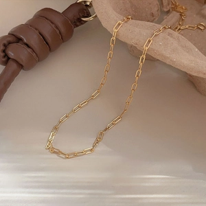 Elegant gold paperclip link chain necklace displayed on a minimalist beige aesthetic surface