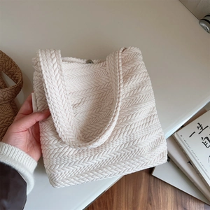Detail of herringbone weave texture and magnetic closure on beige knit shoulder bag