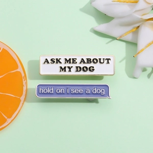 Detail view of cartoon enamel pins featuring Ask Me About My Dog and purple dialog bubble text