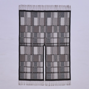 Ethnic knit shawl with black white gray plaid pattern and tassels in a loose poncho style