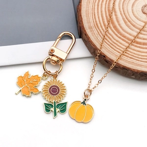 Detail of sunflower and maple leaf enamel charms on gold keychains and necklaces
