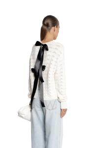 Detail of white hollow-out knit sweater featuring three large black satin bows on open back
