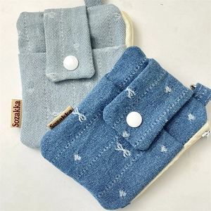 Detailed close-up of textured denim card holders with white stitching and snap button