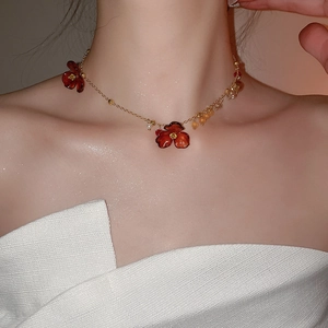 Detail of vintage necklace with acrylic red flowers and white pearls on golden chain