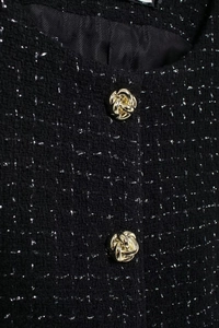 Détail du tissu en tweed noir avec fils métalliques argentés et boutons dorés