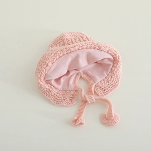 Pink lace knit baby bonnet with earflaps and pom-pom ties for winter warmth