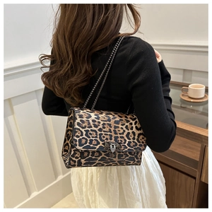 Detalle del bolso con estampado de leopardo y correa de cadena negra en escena cotidiana