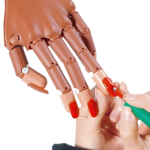 Detail of a brown flexible manicure training hand with movable joints and red nail polish