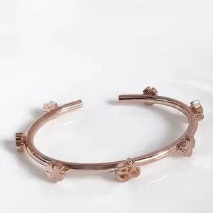 Elegant rose gold stainless steel open bangle with polished four-leaf clover charms