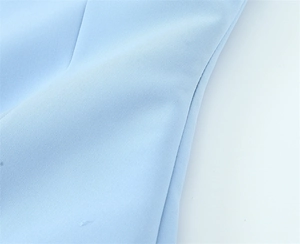 Macro view of light blue woven fabric texture and stitching on a minimalist top