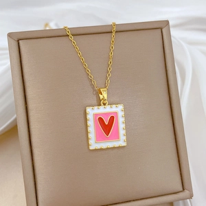 Close-up of gold titanium necklace with square red heart enamel pendant on silk