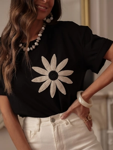 Close-up of 3D knit floral embroidery on black crew neck short sleeve t-shirt