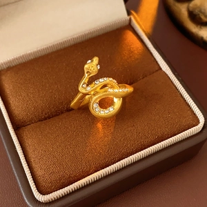 Macro detail of a gold snake ring with sparkling white zircon inlay on brown velvet