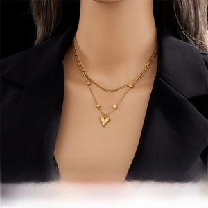 Vue détaillée du collier doré à double rang avec pendentif cœur sur un blazer noir